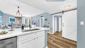 Una cocina moderna con una isla central, armarios blancos y piso de madera.