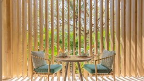 Eine hölzerne Pergola mit einem runden Tisch und zwei Stühlen mit Kissen.