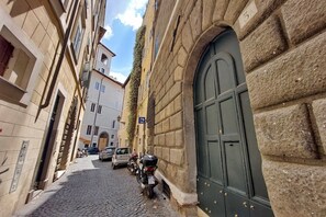 A narrow cobblestone street with buildings on either side, a parked motorcycle, and a green door on the right. - Montevecchio2 - Charming apartment for 4 close to piazza Navona (Roma)