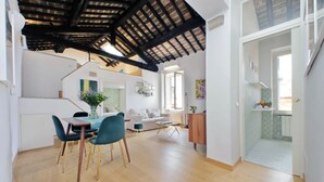 A spacious living area with a dining table, chairs, and a staircase leading to an upper level.