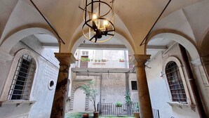 An interior courtyard with arches, a hanging light fixture, and potted plants.