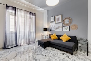 Un salon comprenant un canapé, un pouf et des œuvres d’art décoratives accrochées au mur.
