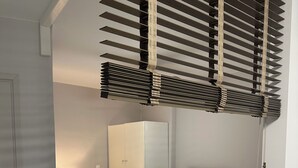 Et moderne hotelværelse med seng, natbord, lampe, garderobeskab og et vindue med persienner.