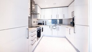 Una cocina moderna con armarios blancos, electrodomésticos de acero inoxidable y una isla central.