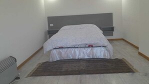 Ein Schlafzimmer mit einem Bett, zwei Wandleuchten, einer Heizung und einem braunen Teppich.