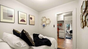 A bedroom with a bed, a rug, and a kitchen visible through an open door. - Quaint Heart of Downtown Flagstaff Unit w/Spa & AC (Flagstaff)