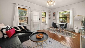 A modern living room with a black leather sofa, a round coffee table, and a dining area with a table and chairs. - Quaint Heart of Downtown Flagstaff Unit w/Spa & AC (Flagstaff)