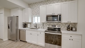 A modern kitchen with white cabinets, stainless steel appliances, and a patterned backsplash. - Lakefront Jackson Vacation Rental w/ Shared Yard (Jackson)