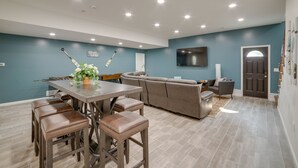 A modern living room with a dining area, a sofa, and a TV mounted on the wall. - Lakefront Jackson Vacation Rental w/ Shared Yard (Jackson)