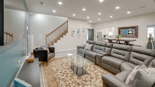 A spacious living room with a large sectional sofa, a glass coffee table, and a staircase leading to another level. - Lakefront Jackson Vacation Rental w/ Shared Yard (Jackson)
