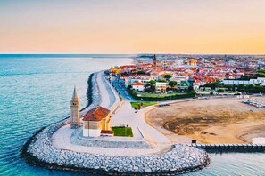 Un pueblo costero con una iglesia destacada, una playa y un muelle de piedra.