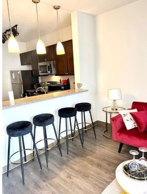 Cozy living space with a kitchen area, featuring a refrigerator, microwave, and stove, and a comfortable sofa.