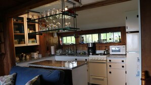 Una cucina compatta con piano cottura integrato, forno a microonde e frigorifero. C'è un'area pranzo con un divano blu e un tavolino da caffè.