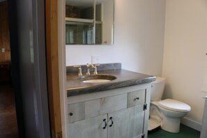 A bathroom with a sink, toilet, and cabinets. - Shipshape (Stonington)