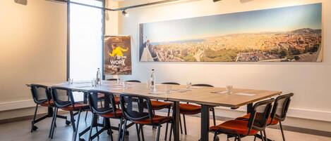 A conference room with a large table, chairs, a poster, and a cityscape view.