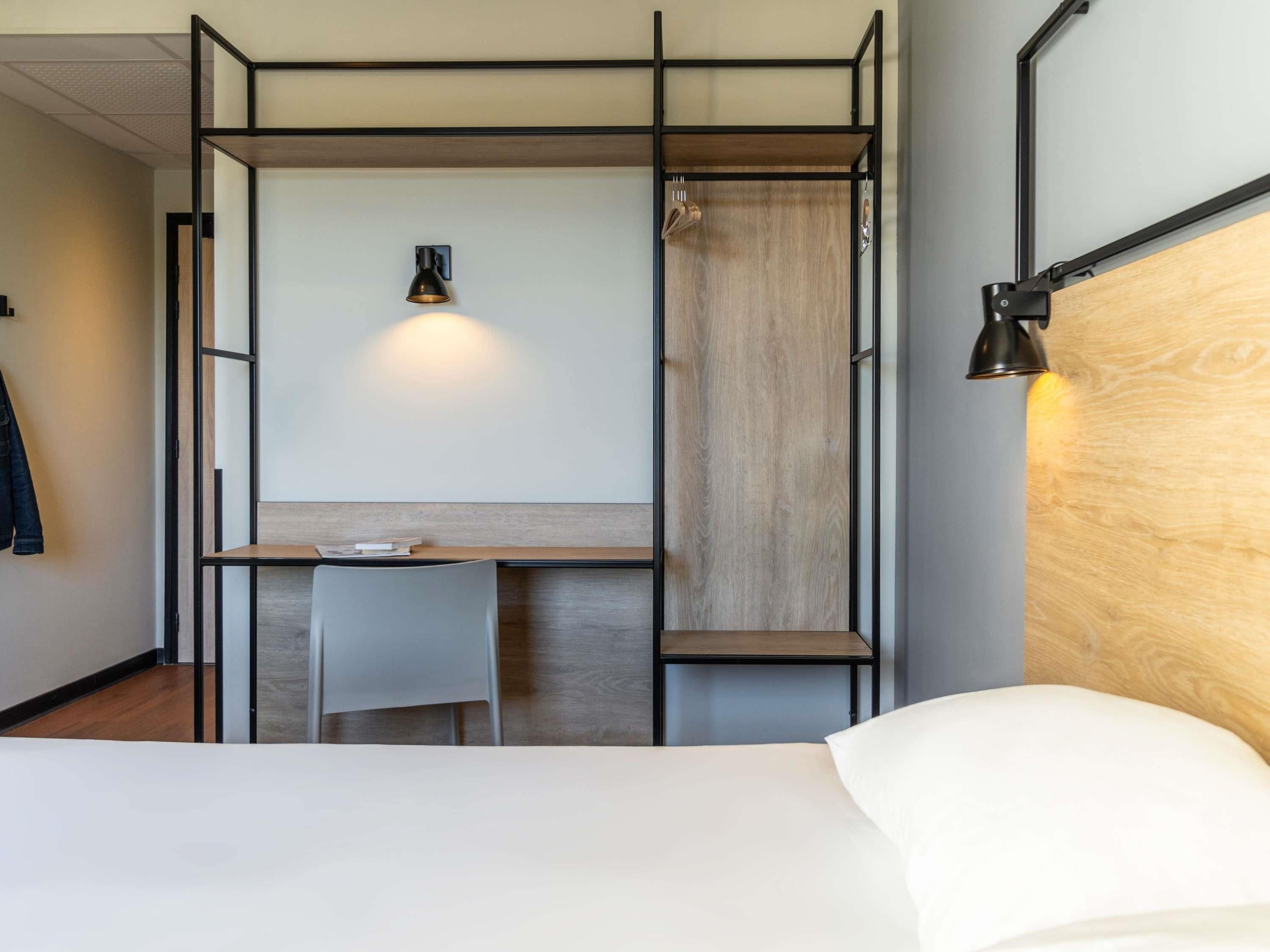 Une chambre d’hôtel de taille réduite, comprenant un lit, un bureau et une chaise.