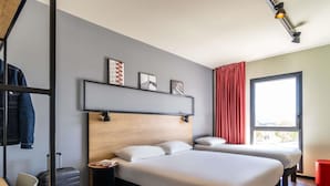 A modern hotel room with a wooden headboard, two beds, a red curtain, and a window with a view. - Ibis Marseille Marignane Technopole (Marignane)