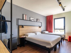 A modern hotel room with a wooden headboard, two beds, a red curtain, and a window with a view.