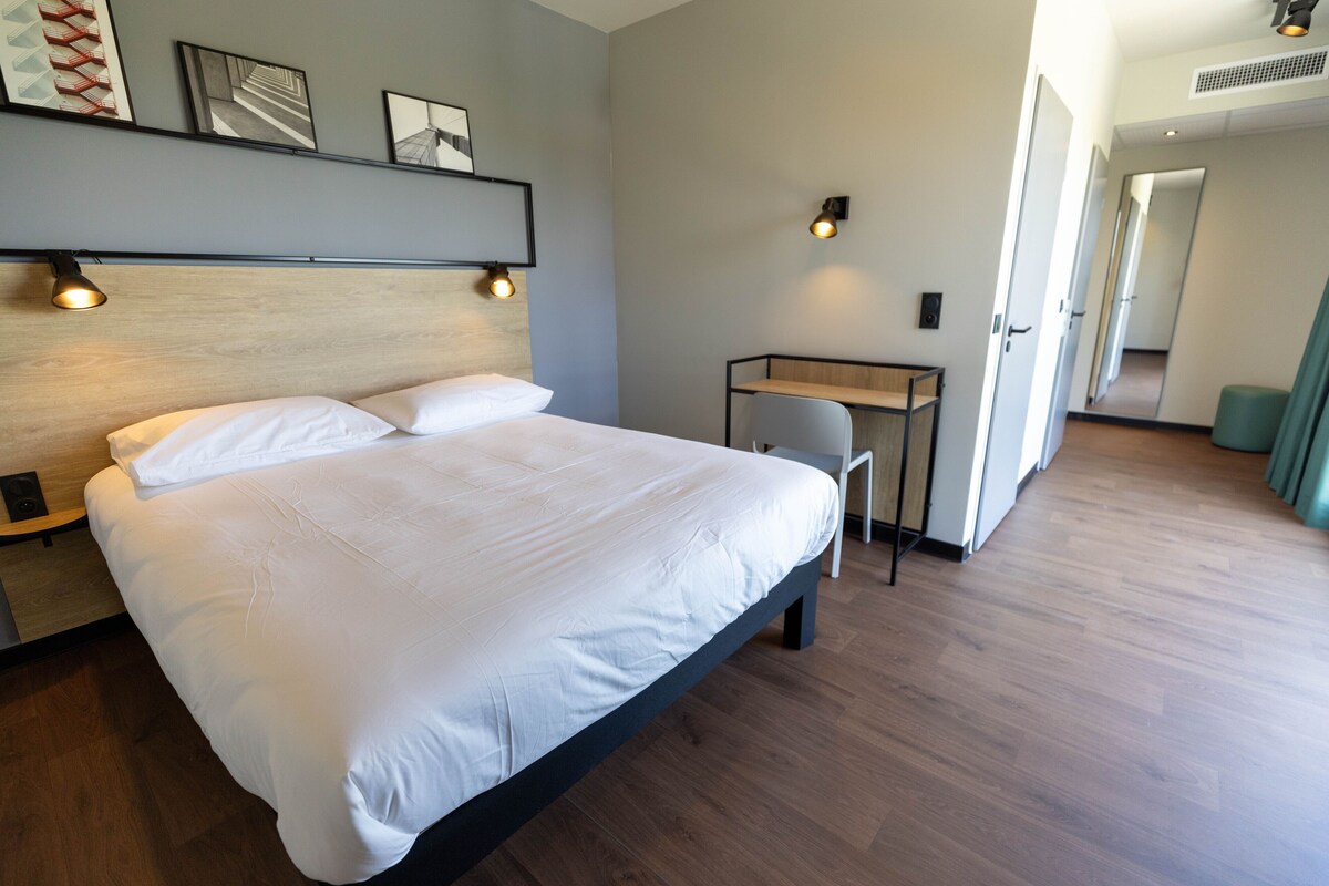 Una habitación de hotel moderna con una cama grande, un escritorio y una silla.