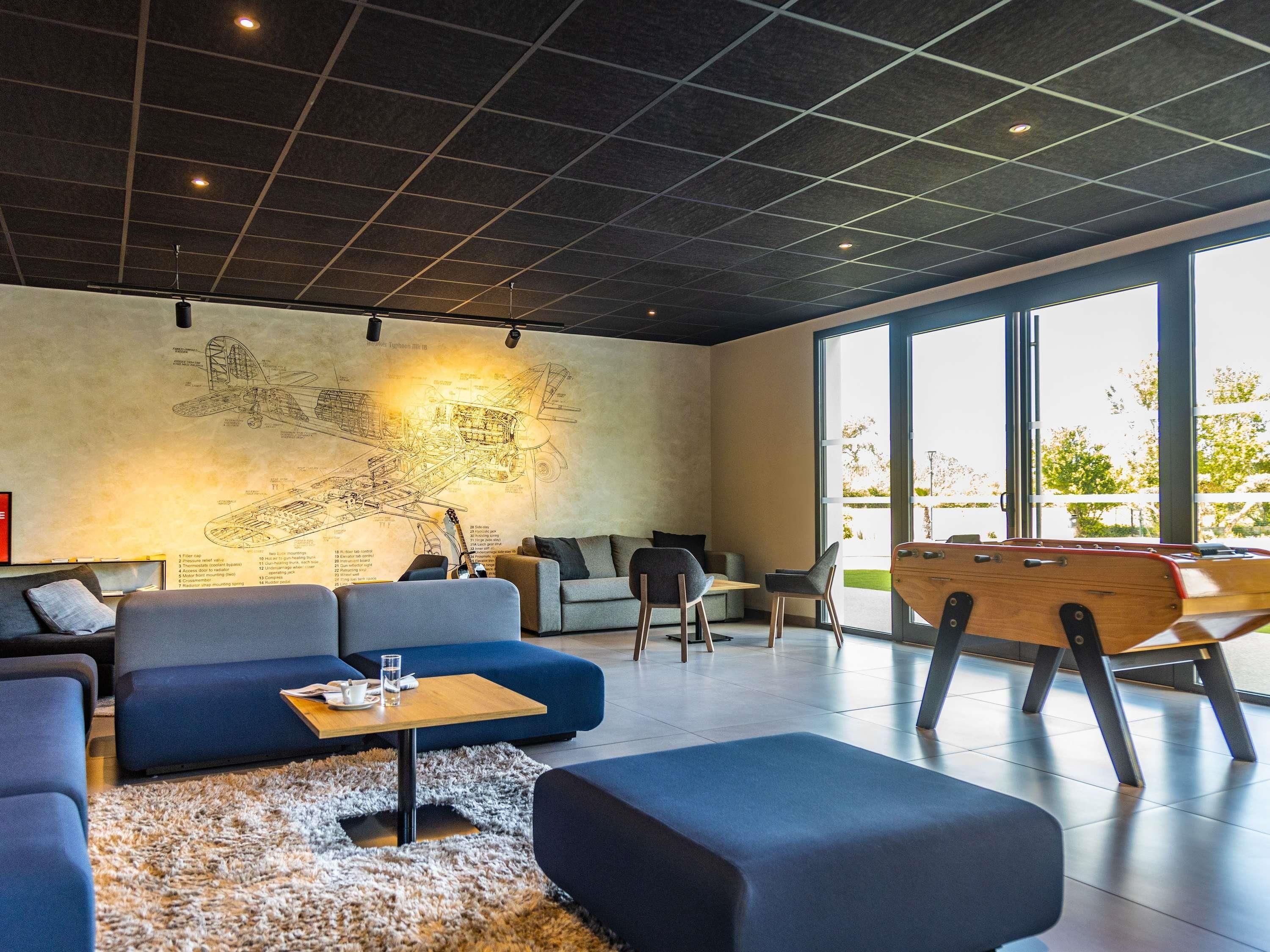 A modern lounge with a large wall mural, comfortable seating, and a wooden play table.