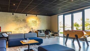 A modern lounge with a large wall mural, comfortable seating, and a wooden play table.