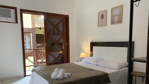 Una cama bien hecha con una manta marrón, una lámpara de noche y un cabecero de madera.