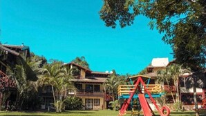 Un resort con varias construcciones, palmeras y un columpio rojo.