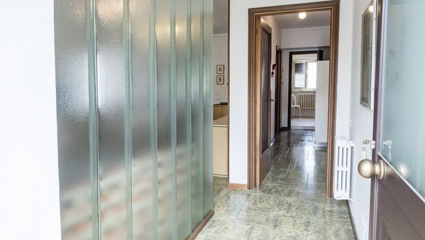 A hallway with a glass partition, a radiator, and a door with a brass handle. - A28 - Poggio, large three-room apartment with porch (Poggio)