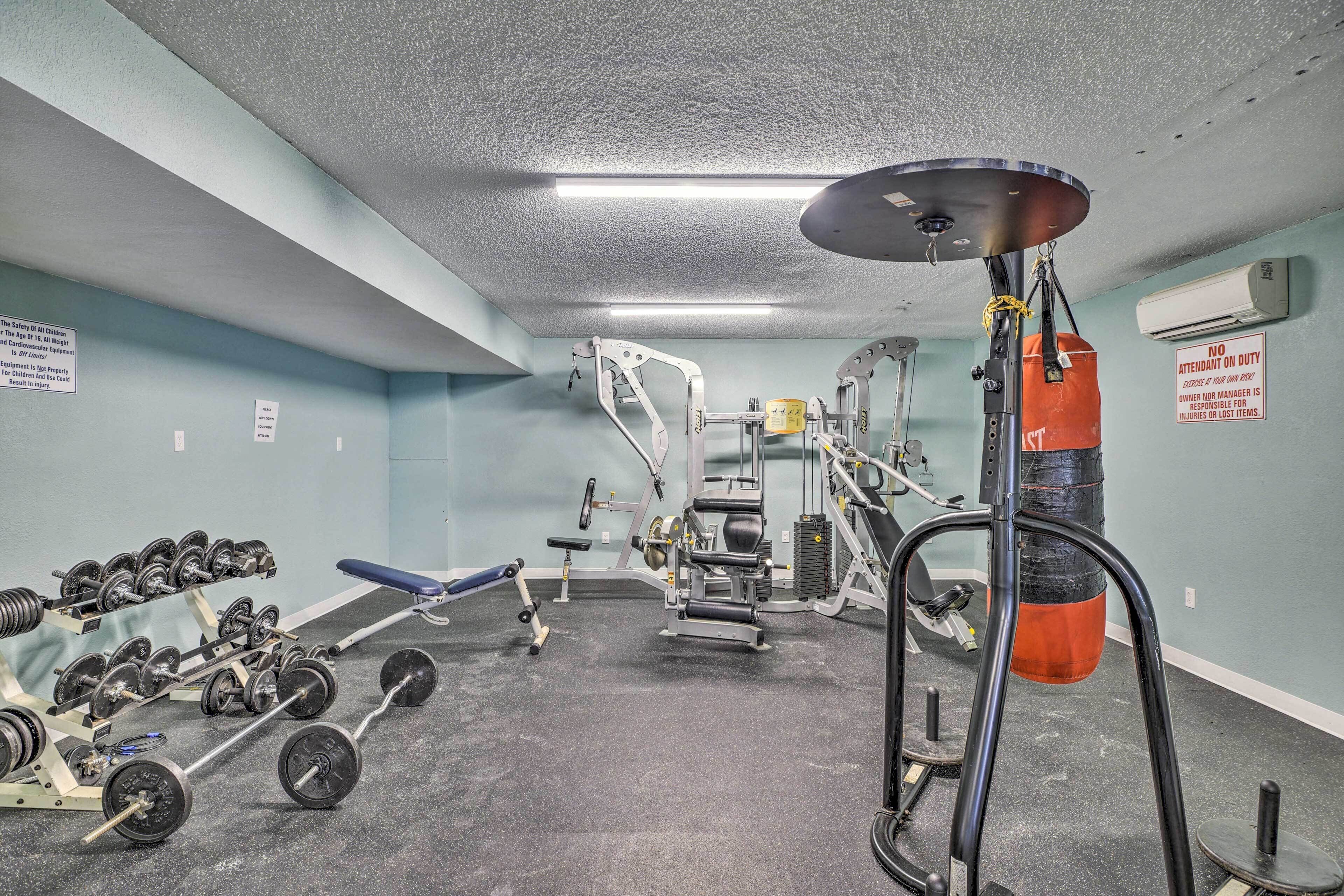 A gym with weightlifting equipment, a punching bag, and a bench.