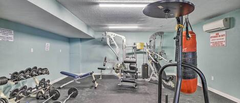 A gym with weightlifting equipment, a punching bag, and a bench.
