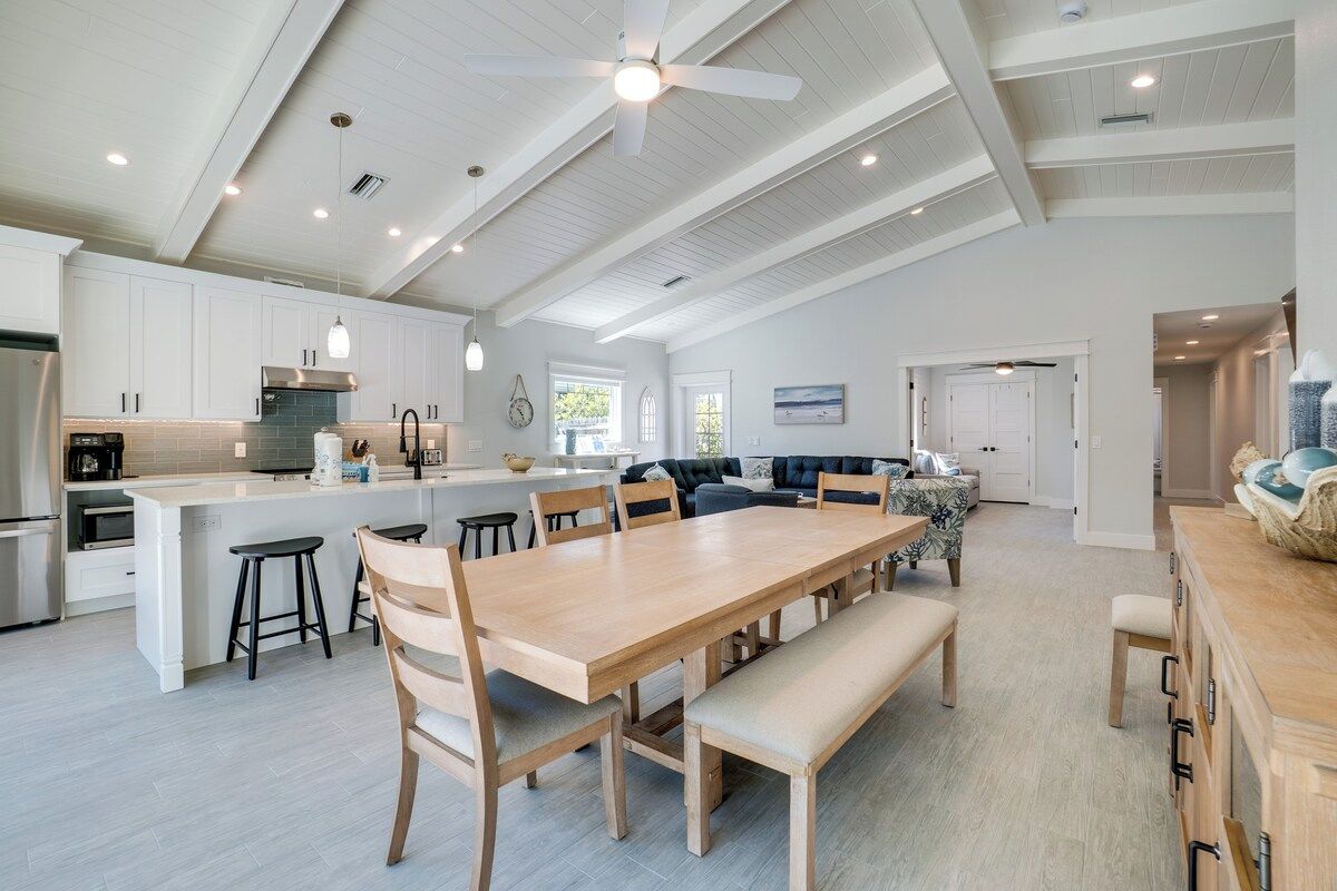 A spacious kitchen with a large island, wooden dining table, and bar stools.