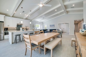 A spacious kitchen with a large island, wooden dining table, and bar stools.