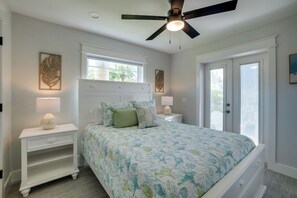 A bedroom with a bed, nightstands, a ceiling fan, and a window.