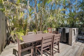 An outdoor patio with a wooden table and chairs, surrounded by palm trees. - Stonehenge (Anna Maria)