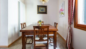 A dining room with a wooden table, chairs, a chandelier, and artwork on the walls. - GuestHost - Apartment located on the first floor of a building, divided into two levels without a lift.In 85 square meters of space it comfortably accommodates four people with two bedrooms located on the second floor. There is an internal staircase.Loca (Venezia)