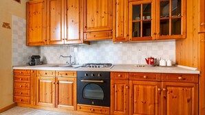 A kitchen with wooden cabinets, a gas stove, an oven, and a sink. - GuestHost - Apartment located on the first floor of a building, divided into two levels without a lift.In 85 square meters of space it comfortably accommodates four people with two bedrooms located on the second floor. There is an internal staircase.Loca (Venezia)