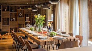 A long wooden dining table set with plates, glasses, and a centerpiece of flowers. - Chalet Arpitania - luxury chalet for 14 with pool and spa - OVO Network (La Clusaz)