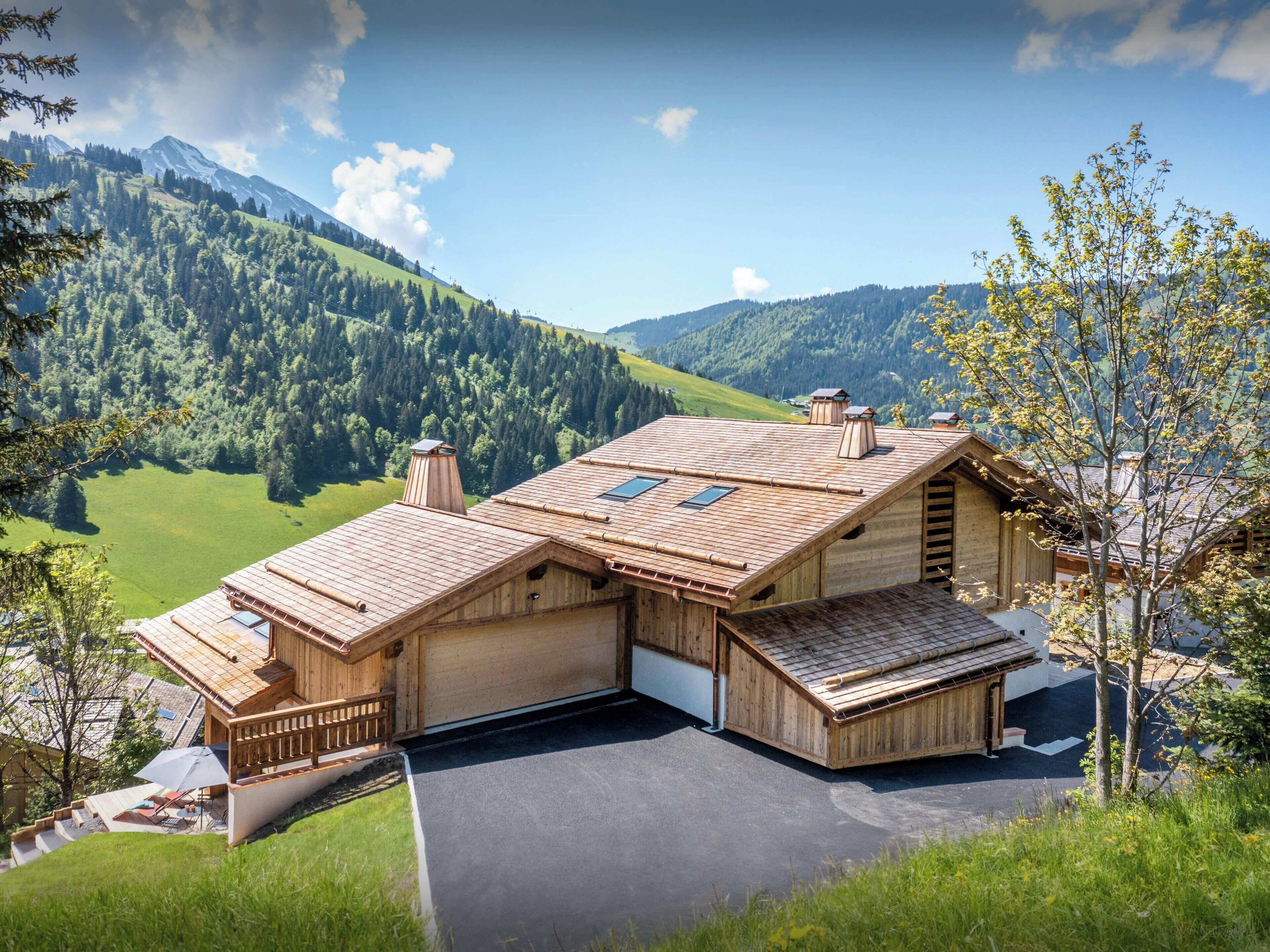 Un chalet in legno con tetto spiovente, un garage e vista su un paesaggio montano.