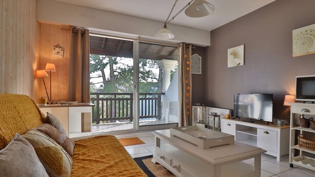 Un salon moderne avec un canapé, une table basse, un téléviseur et un balcon offrant une vue agréable.