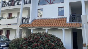 Un immeuble à plusieurs étages, doté de balcons, d’un toit en tuiles et d’une grande fenêtre en arc de cercle.