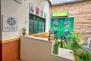 A co-living space named LA GRUCA with a signboard, a bike, and a green wall with posters.