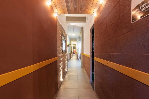 A corridor with brick walls, yellow trim, and a sign indicating a personnel-only area.