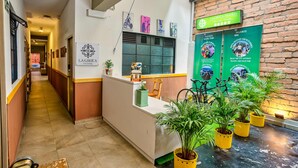 A hallway with a reception desk, potted plants, and a sign for 'LAGRICA-Mobility'. - La Gruta Co-Living  (Medellín)