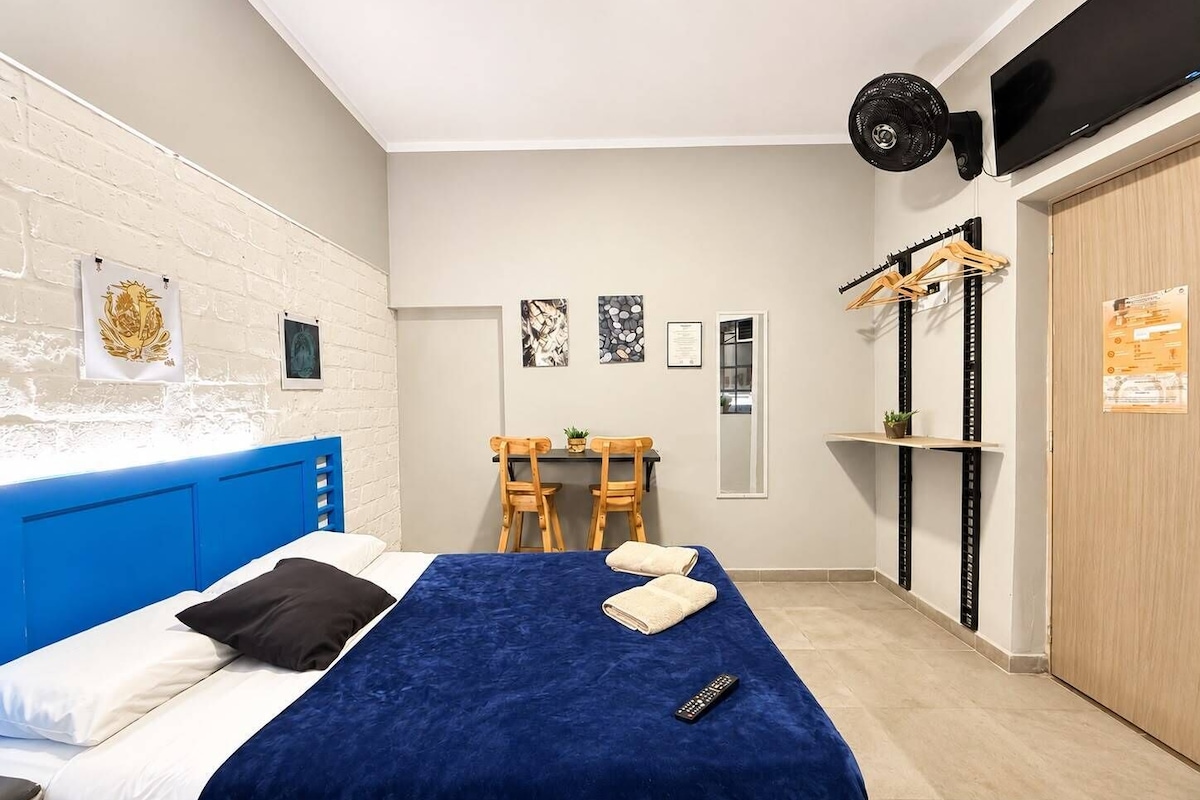 Ein Schlafzimmer mit einem Bett, einem Schreibtisch, Stühlen, einem Kleiderschrank und einem Fernseher.
