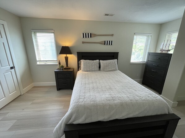 A bedroom with a bed, nightstand, dresser, and two wall-mounted bat decorations. - Harbor Hideaway - private hot tub, stunning views & ideal outdoor space! (Garden City)