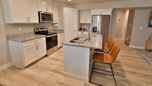 A modern kitchen with white cabinetry, stainless steel appliances, and a granite countertop. - 227 - Bear Lake Escapes. Beautiful Home in an Unbeatable Location (Garden City)