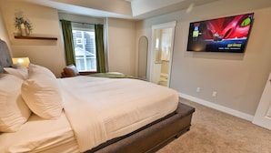 A bedroom with a large bed, a TV on the wall, a window with curtains, and a small table with a remote control. - 227 - Bear Lake Escapes. Beautiful Home in an Unbeatable Location (Garden City)