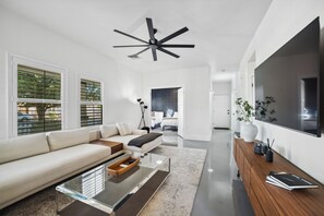 Ein modernes Wohnzimmer mit Sofa, Couchtisch und einem an der Wand montierten Fernseher.