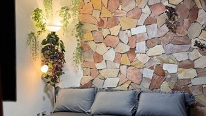 A modern living room with a sectional sofa, a stone wall, and hanging plants.