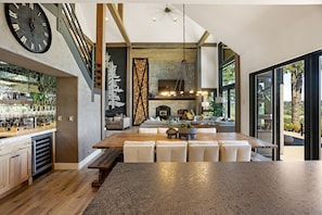 Una cocina moderna con una isla grande, una chimenea de piedra y un comedor con vistas al exterior.